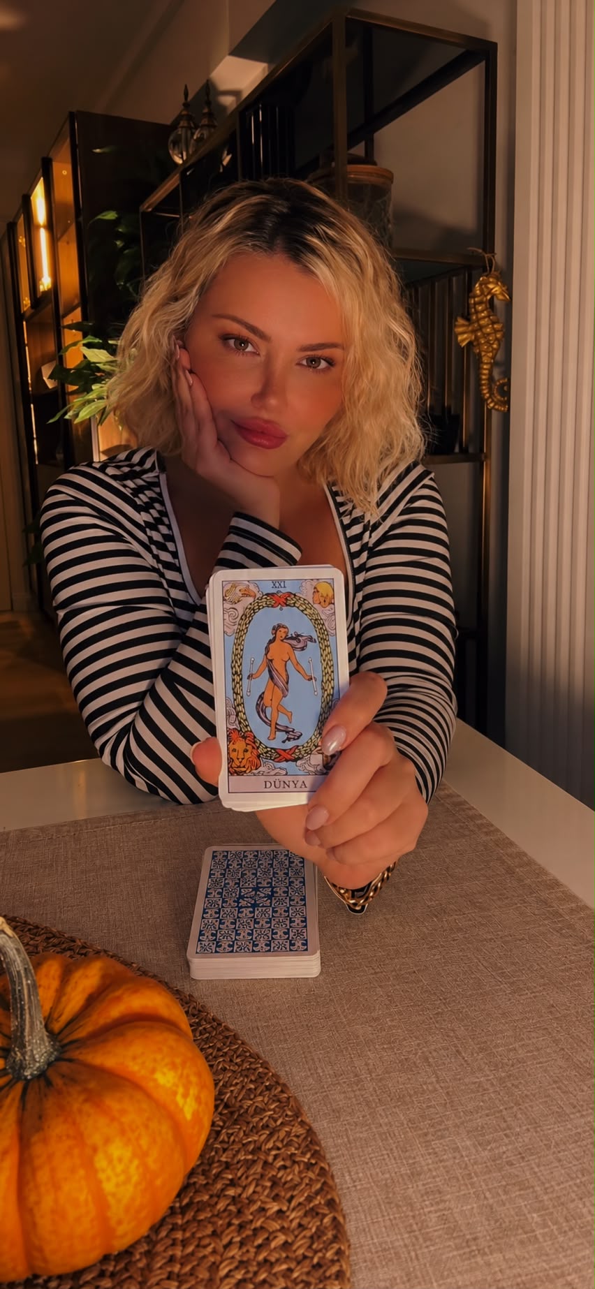 Gina, psychic medium of Gina Medium Studio, holding The World tarot card at her reading table